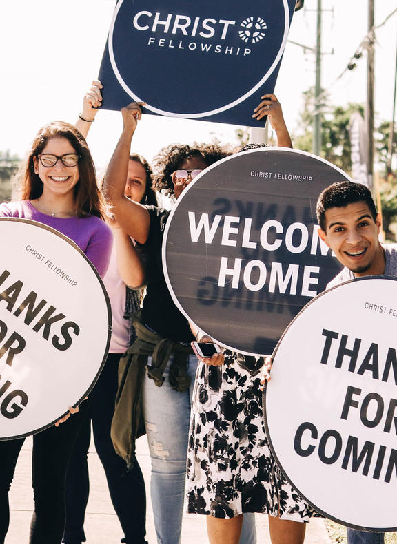 Group of young adults holding welcome signs